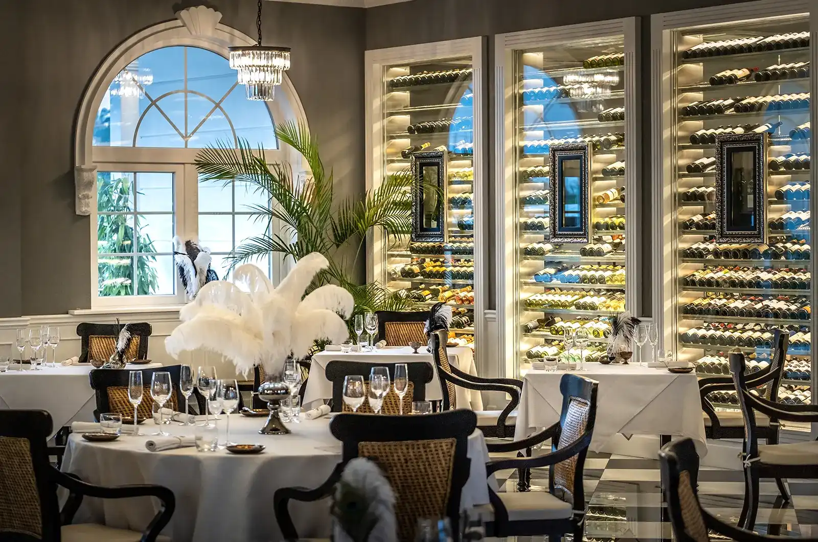 Elegant fine dining restaurant with chandeliers, wine racks, and feather centerpiece