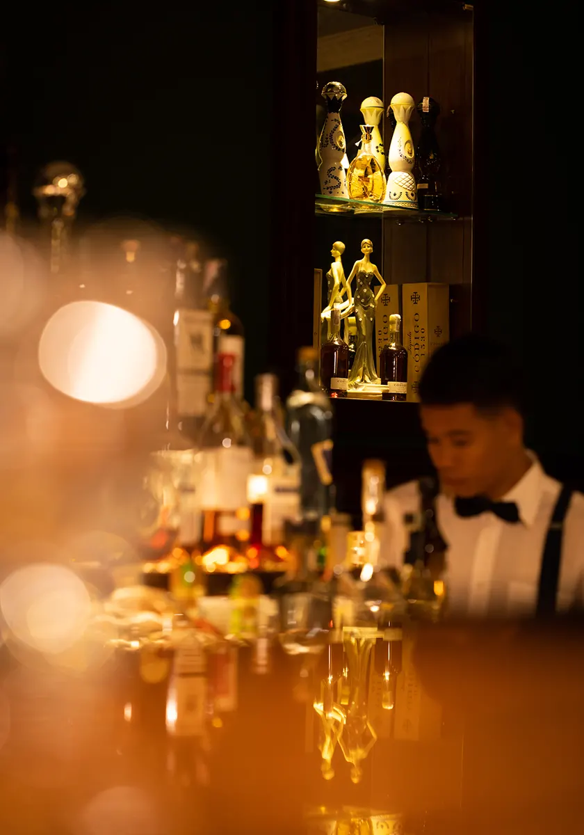 A staff member standing next to some alcohol bottles