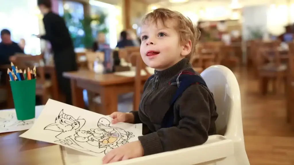 A child at a fine dining restaurant holding a colouring book