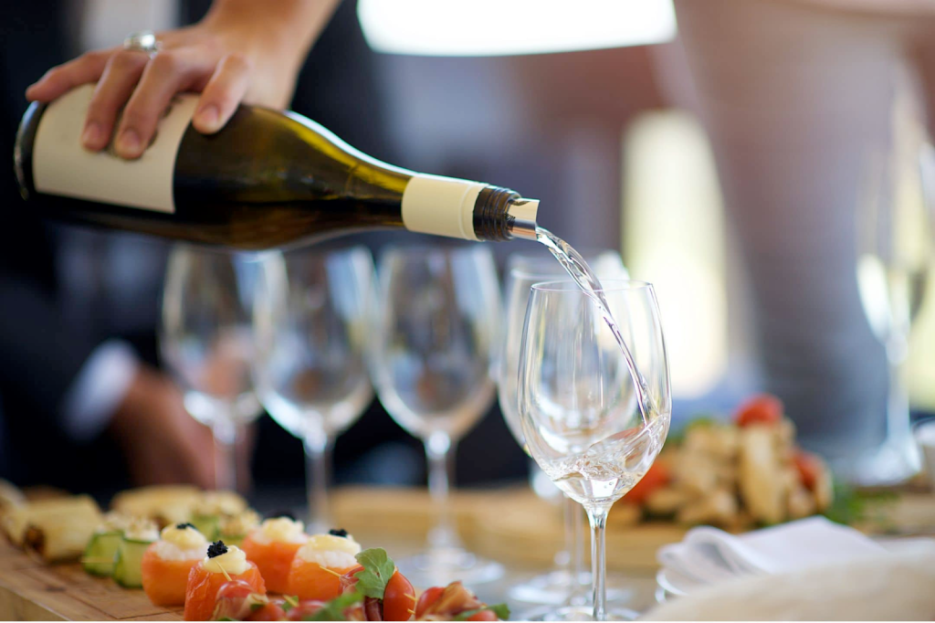 Wine poured into wine glasses next to fine dining canapé dishes