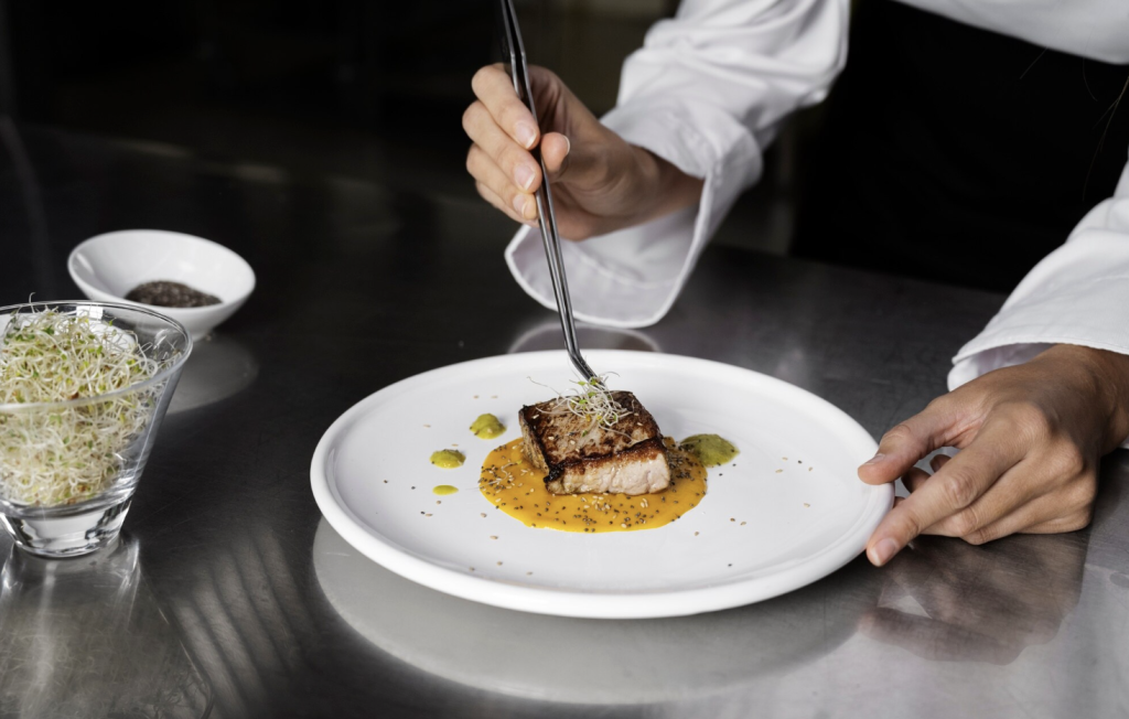 A Michelin chef plating a gourmet fish meal