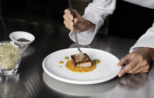 A Michelin chef plating a gourmet fish meal
