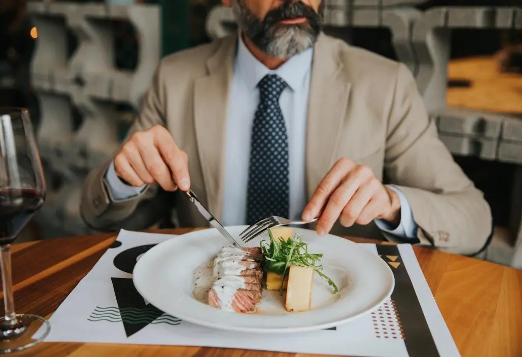 A diner eating an elegant meal with a knife and fork