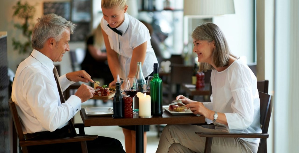 Two diners being served a meal from a waitress