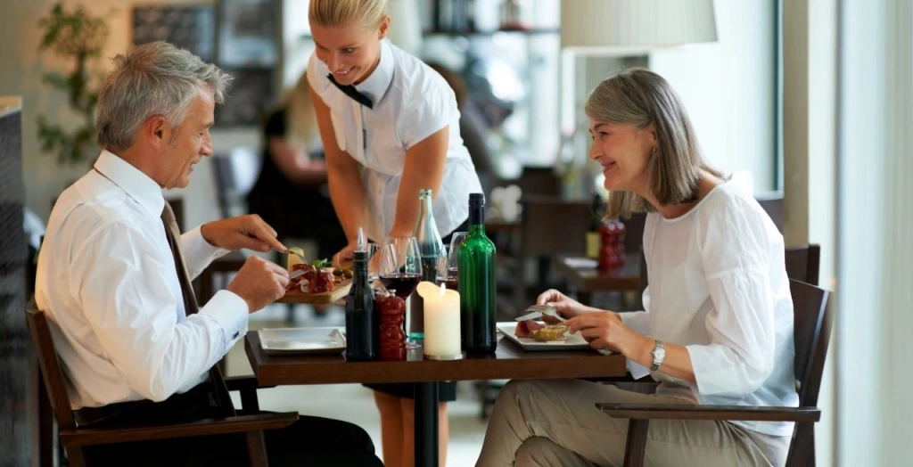 Two diners being served a meal from a waitress