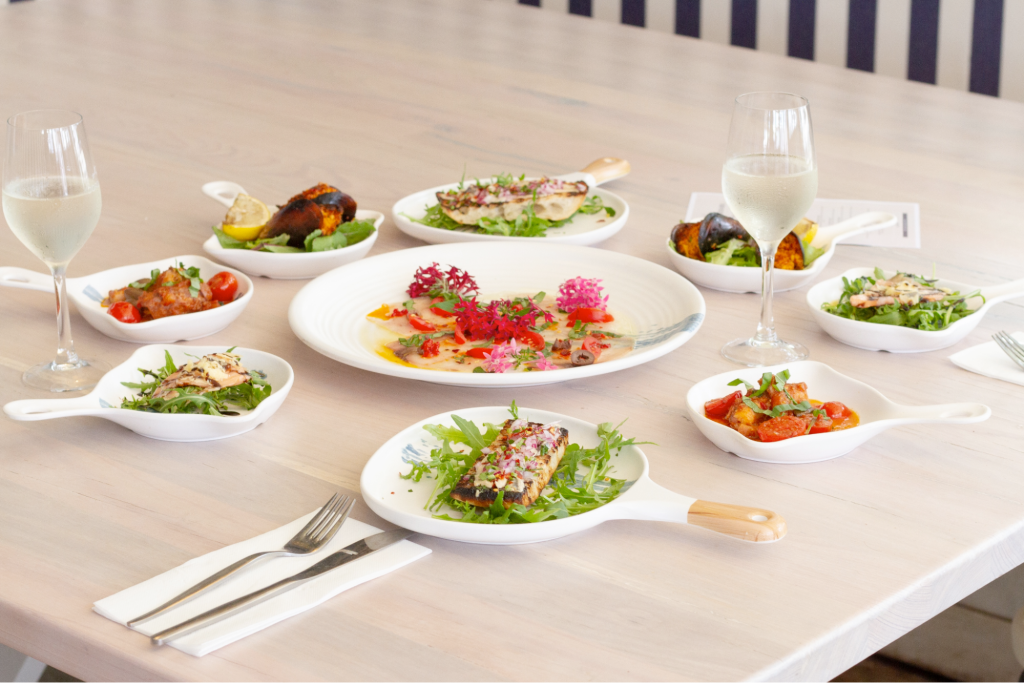 An array of fine dining style meals with two glasses of wine