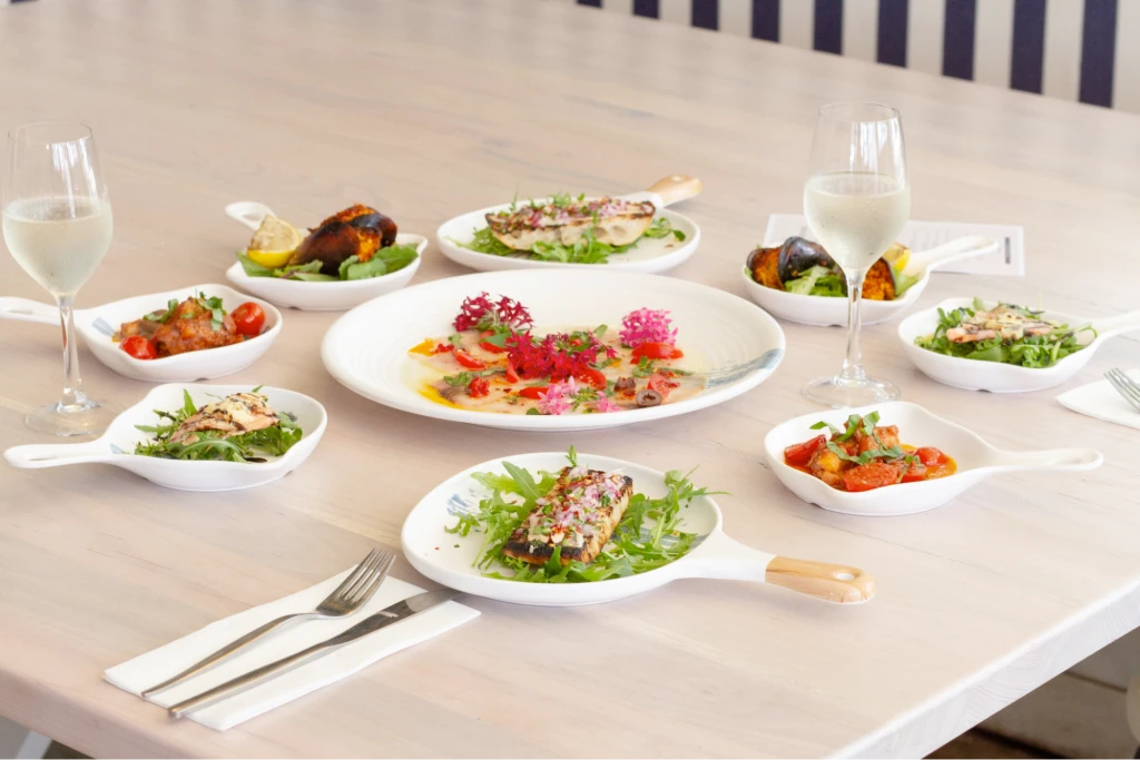 An array of fine dining style meals with two glasses of wine