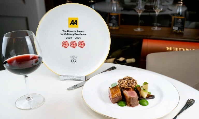 A gourmet meal and glass of red wine sitting beside an AA Rosette award plate