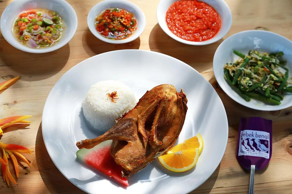 A Balinese style chicken with rice dish with sambals on the side