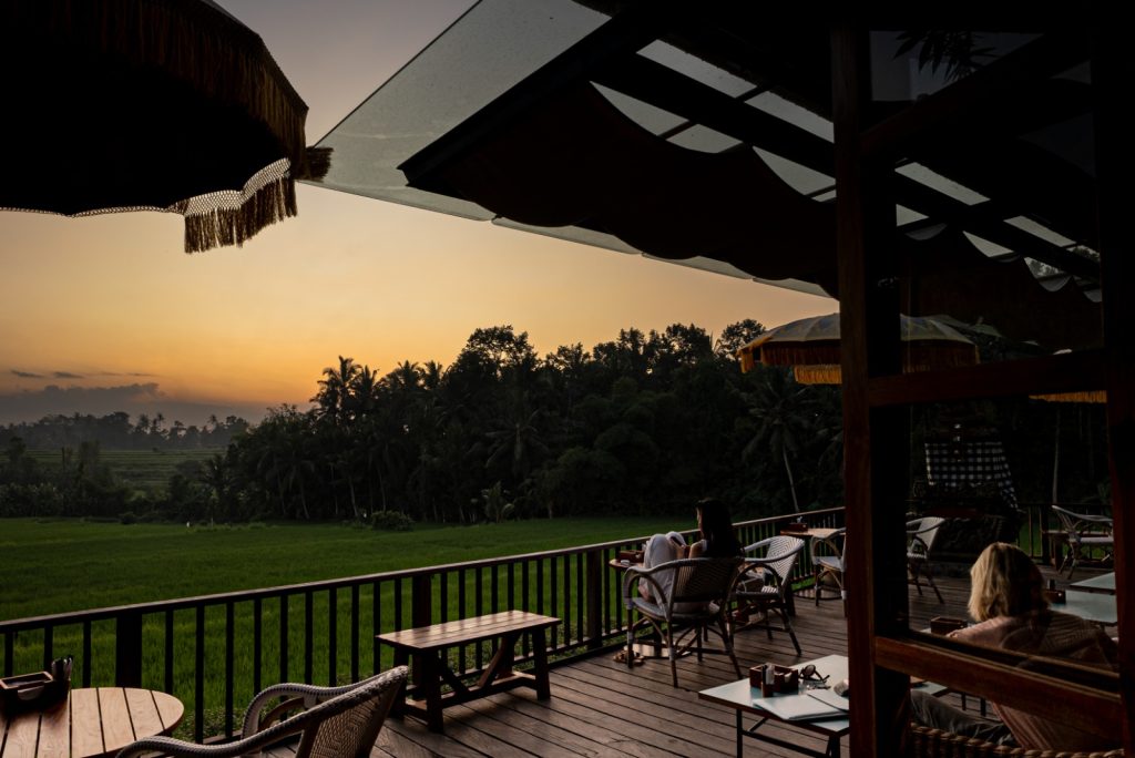 A sunset and view of rice paddies and palm trees from RÜSTERS Restaurant in Ubud