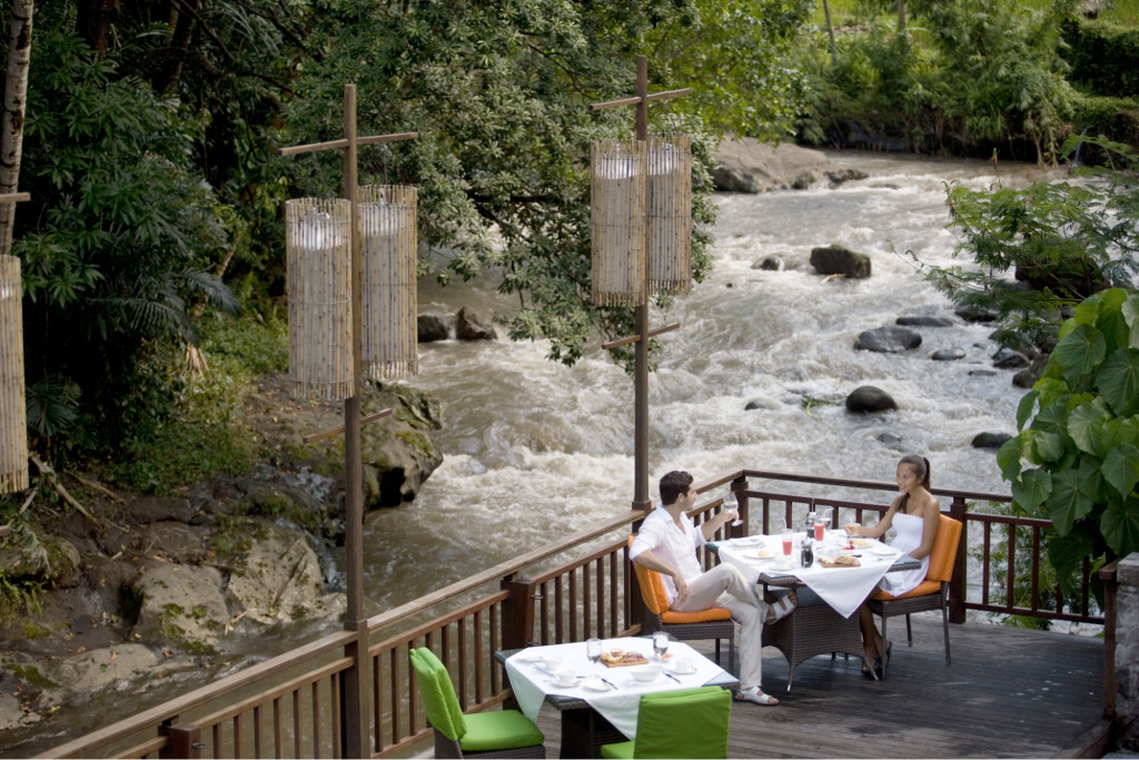 Two diners at table beside a river in Ubud, Bali