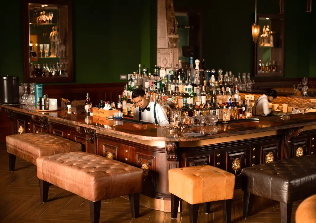 Bartender in bow tie preparing drinks at elegant upscale bar