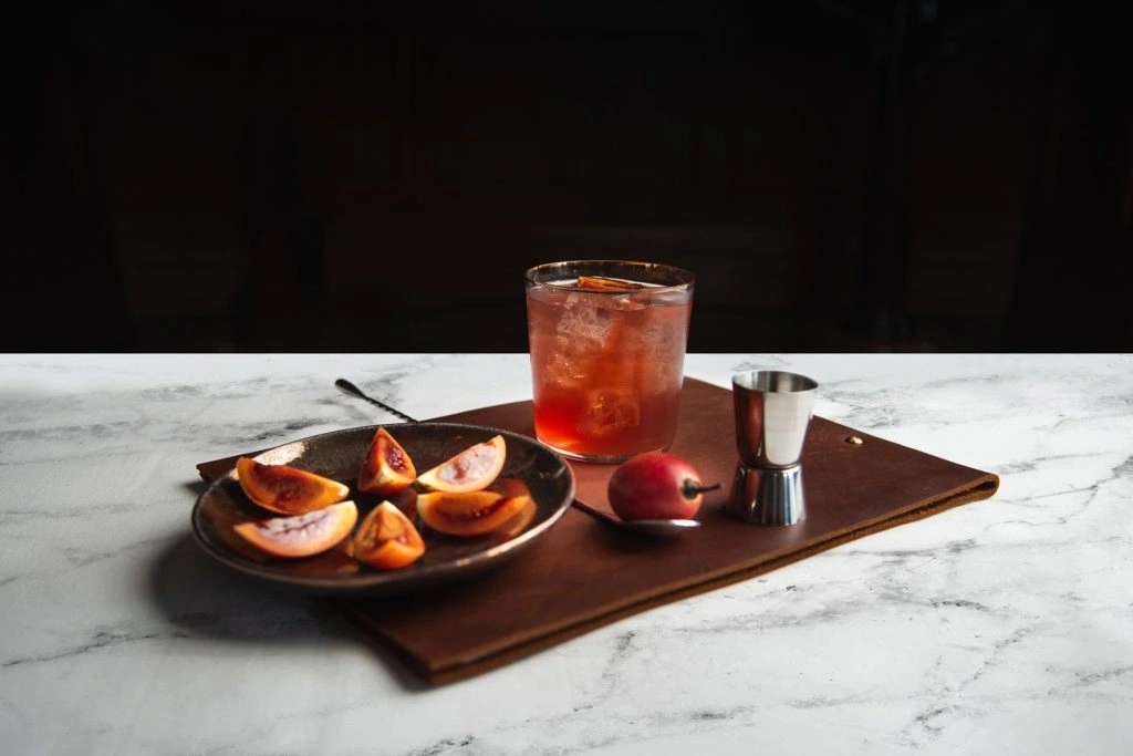 Iced red cocktail served with sliced exotic tamarillo fruit platter