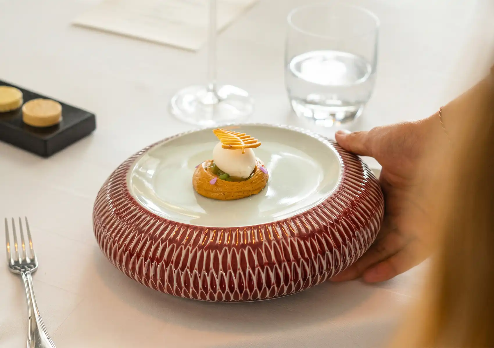 Sensorial dining experience with gourmet plated dessert featuring mousse sphere, lattice garnish, and artistic fine dining presentation.