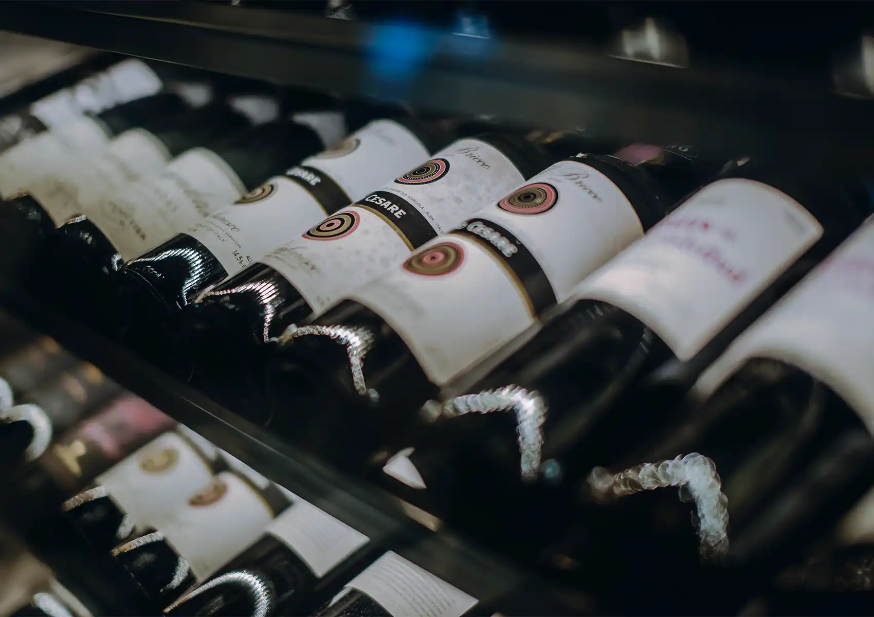 Close-up of premium wine bottles resting horizontally on a cellar rack, showcasing the extensive selection available for wine pairing fine dining Bali.