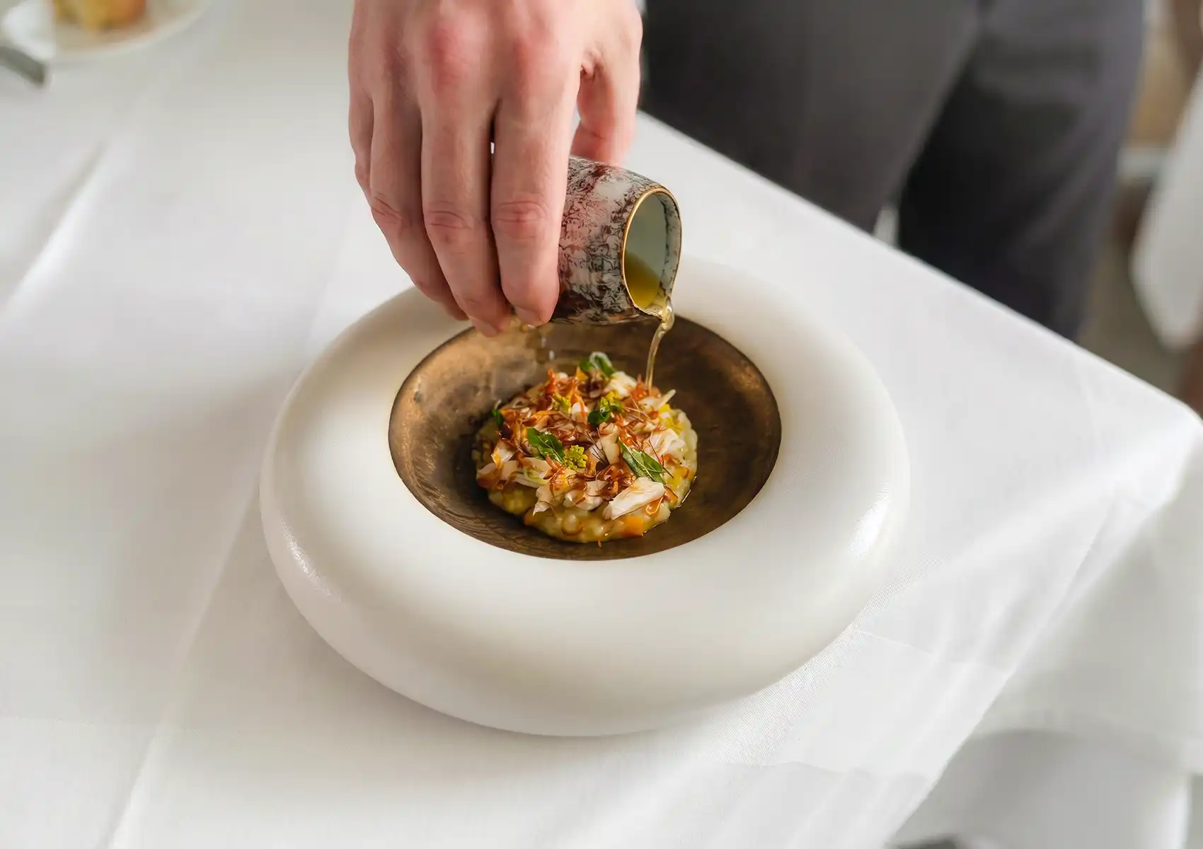 A server pouring sauce over an exquisite degustation dish, perfect for a celebratory fine dining meal during Indonesian Independence Day Bali.