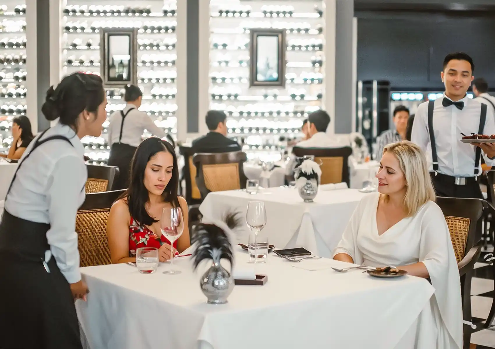 A waitress serving a beautifully plated gourmet dish to a guest who is taking a photo of his meal with a smartphone at a fine dining Ubud establishment.